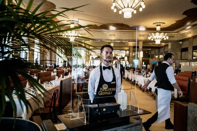 A waiter works on June 15, 2020 in Lyon, on the re-opening day of the Brasserie Georges, as part of the easing of lockdown measures taken to curb the spread of the COVID-19 pandemic, caused by the novel coronavirus. (Photo by Jeff Pachoud/AFP Photo)