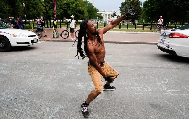 A protestor dances in the street as demonstrators face off with police at the intersection of 16th and H Street on Black Lives Matter Plaza along Lafayette Park across from the White House after Washington Metropolitan Police officers pushed back racial inequality protestors to re-open the street for the resumption of vehicle traffic in Washington, D.C., U.S., June 22, 2020. (Photo by Joshua Roberts/Reuters)
