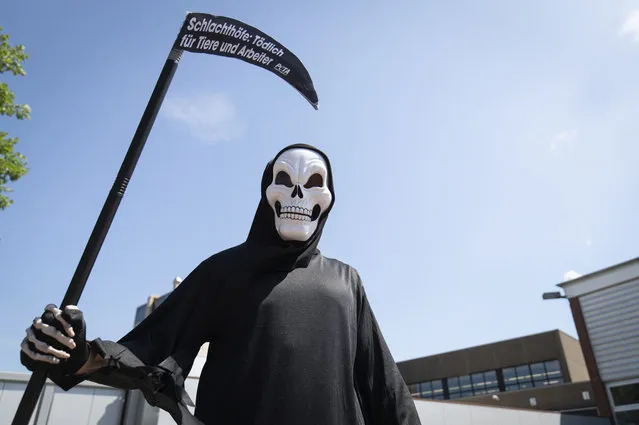 An activist of the animal protection organization Peta disguised as death stands in front of a delivery entrance of the meat and sausage manufacturer Schulte in Dissen, Germany, Thursday, June 25, 2020. Schulte belongs to the Tönnies Group. Under the motto “Slaughterhouses: Deadly for humans and animals”, Peta wants to draw attention to the conditions in meat factories after the outbreak of the coronavirus at meat producers. (Photo by Friso Gentsch/dpa via AP Photo)