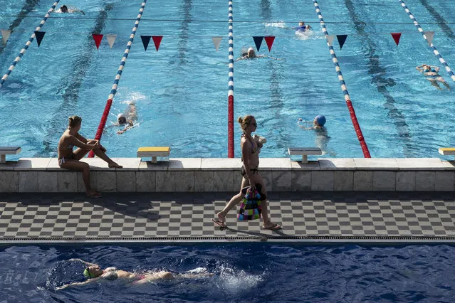 People enjoy the first day after the reopening of Chaika open air pool in Moscow, Russia, Thursday, June 25, 2020. Russian capital's gyms and pools opens these week after three months of coronavirus shutdown. (Photo by Pavel Golovkin/AP Photo)