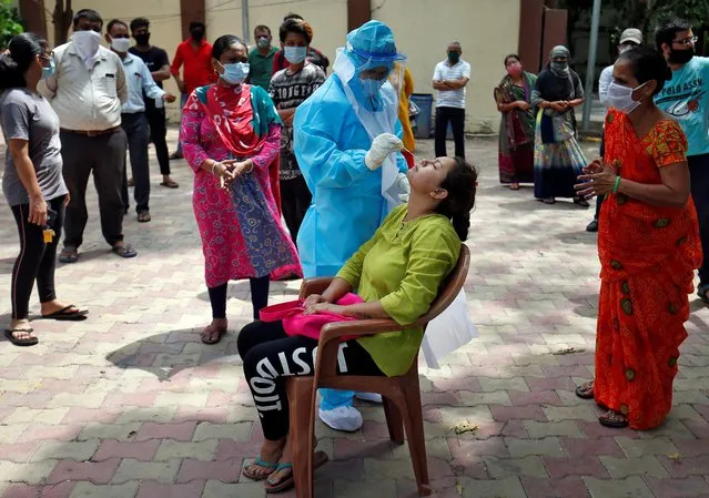 A healthcare worker wearing Personal Protective Equipment (PPE) takes swab from a woman to test for the coronavirus disease (COVID-19) at a residential area in Ahmedabad, India, July 8, 2020. (Photo by Amit Dave/Reuters)