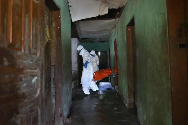 An Ebola burial team, dressed in protective clothing, carries the body of a woman, 54, from the bedroom where she died in the New Kru Town suburb on October 10, 2014 of Monrovia, Liberia. The World Health Organization says the Ebola epidemic has now killed more than 4,000 people in West Africa. (Photo by John Moore/Getty Images)