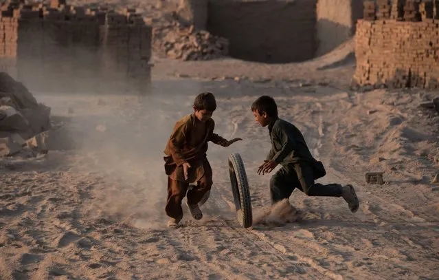 In this photograph taken on July 27, 2016, Afghan children play with a tyre along a dusty  road on the outskirts of Jalalabad. (Photo by Noorullah Shirzada/AFP Photo)