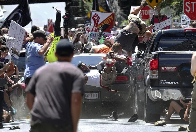 People are thrown into the air as a car drives into a group of protesters demonstrating against a white nationalist rally in Charlottesville, Va., on August 12, 2017. The white nationalists were holding the rally to protest plans by the city of Charlottesville to remove a statue of Confederate Gen. Robert E. Lee. There were several hundred counterprotesters marching in a long line when the car drove into a group of them. (Photo by Ryan M. Kelly/The Daily Progress via AP Photo)