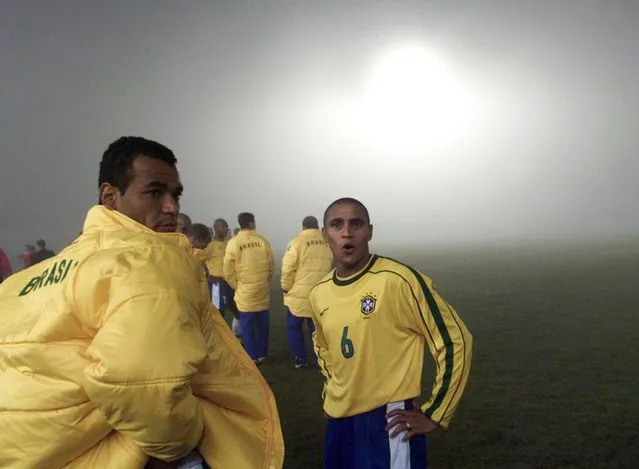 Brazil's Cafu (L) and Roberto Carlos stand together in the fog-covered field after their Copa America game against Chile was suspended by the referee with five minutes left of the second half in Ciudad del Este, Paraguay, July 6, 1999. Brazil were eventually awarded the victory after leading the match 1-0. (Photo by Andrew Winning/Reuters)