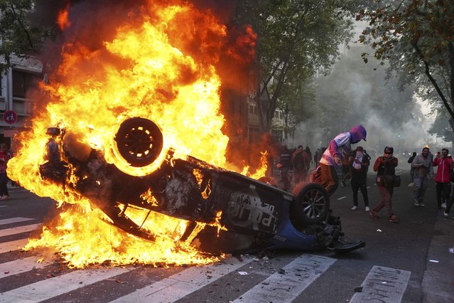 A protester burns a police car during a demonstration by soccer fans join and retirees demanding higher pensions and opposing austerity measures implemented by Javier Milei's government in Buenos Aires, Argentina, Wednesday, March 12, 2025. (Photo by Rodrigo Abd/AP Photo)