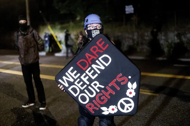 Stacy Kendra Williams holds a shield while facing off against police at the Penumbra Kelly Building on Thursday, September 3, 2020, in Portland, Ore. This weekend Portland will mark 100 consecutive days of protests over the May 25 police killing of George Floyd.  (Photo by Noah Berger/AP Photo)
