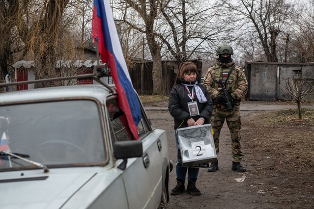 A member of a local election commission, accompanied by a serviceman, visits voters during early voting in Russia's presidential election in Donetsk, Russian-controlled Ukraine, amid the Russia-Ukraine conflict on March 14, 2024. (Photo by AFP Photo/Stringer)