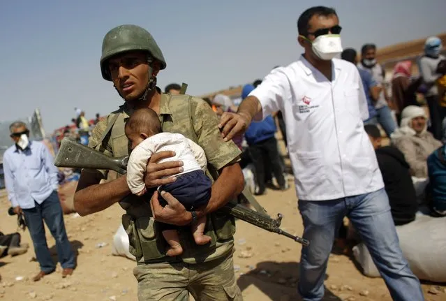 A Turkish soldier carries a Syrian Kurdish refugee baby from the Syrian border town Kobani, near the southeastern Turkish town of Suruc in Sanliurfa province in this October 2, 2014 file photo. (Photo by Murad Sezer/Reuters)