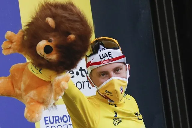 Stage winner and new overall leader, wearing the yellow jersey, celebrates with the mascot on the podium after stage 20 of the Tour de France cycling race, an individual time trial over 36.2 kilometers (22.5 miles), from Lure to La Planche des Belles Filles, France, Saturday, September 19, 2020. (Photo by Christophe Ena/AP Photo/Pool)