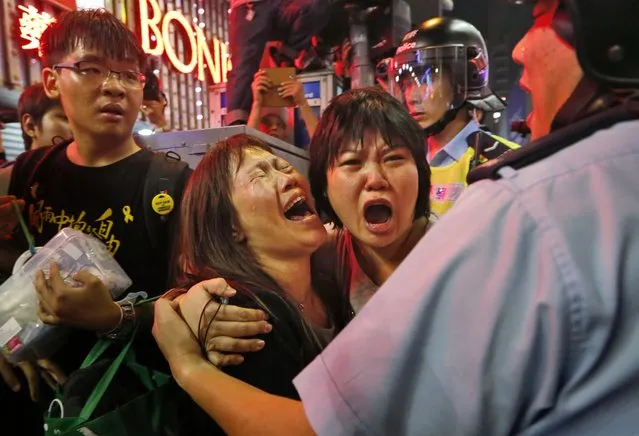 Protesters cry as the police officers try to stop them blocking the road in Mong Kok district of Hong Kong Wednesday November 26, 2014. Police arrested key student leaders of Hong Kong's pro-democracy protests on Wednesday as they cleared barricades in one volatile district, throwing into doubt the future of a 2-month-old movement seeking free elections in the former British colony. (Photo by Kin Cheung/AP Photo)