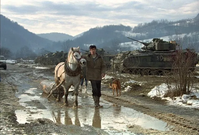 In this Sunday, January 7 1996 file photo, a Bosnian farmer guides his horses passing the base of the U.S. Alpha advance team of the 3/4 Cav. in Staric, a Bosnian village 40 kilometers (24 miles) south of Tuzla, as the deployment of U.S. forces into Bosnia continues. (Photo by Karsten Thielker/AP Photo/File)