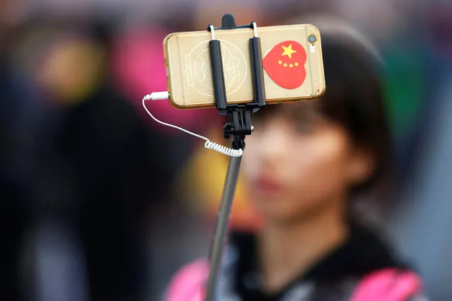 A woman takes pictures of herself as people gather in Tiananmen Square to celebrate National Day marking the 67th anniversary of the founding of the People's Republic of China, in Beijing October 1, 2016. (Photo by Damir Sagolj/Reuters)