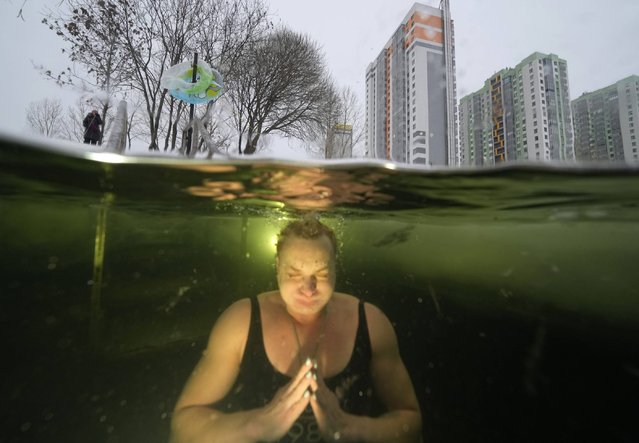 A woman bathes in an ice hole in a pond in St. Petersburg, Russia, Tuesday, January 4, 2022. The temperature in St. Petersburg is –7C (19F). (Photo by Dmitri Lovetsky/AP Photo)