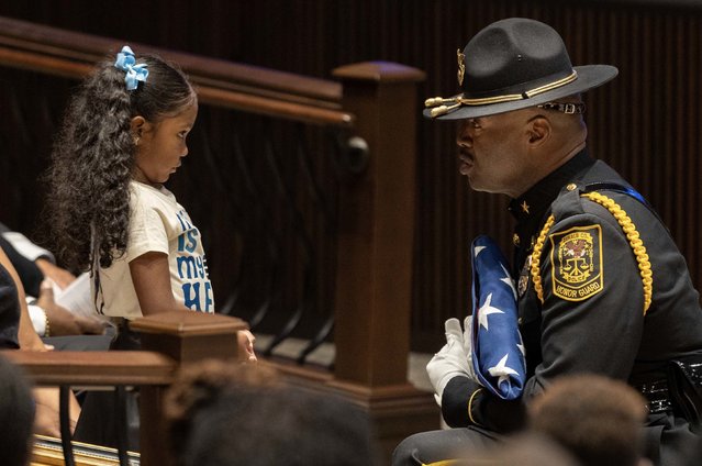 A member of the DeKalb County Police honor guard hands a flag to the daughter of police officer David Rose during Rose's funeral in Atlanta on Friday, August 22, 2025. Rose was killed while responding to a shooting earlier this month on the campus of the Centers for Disease Control and Prevention. He was 33. (Photo by Arvin Temkar/Atlanta Journal-Constitution/AP Photo)