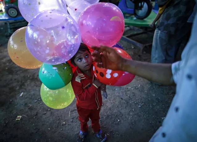 Five-year-old Sonu holds balloons as he helps his father at a fair in Mumbai December 8, 2014. (Photo by Danish Siddiqui/Reuters)
