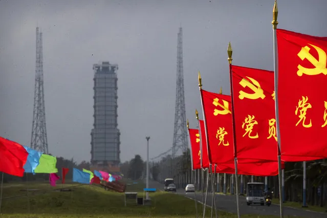 Flags with the logo of the Communist Party of China fly in the breeze near a launch pad at the Wenchang Space Launch Site in Wenchang in southern China's Hainan province, Monday, November 23, 2020. Chinese technicians were making final preparations Monday for a mission to bring back material from the moon's surface for the first time in nearly half a century — an undertaking that could boost human understanding of the moon and of the solar system more generally. (Photo by Mark Schiefelbein/AP Photo)