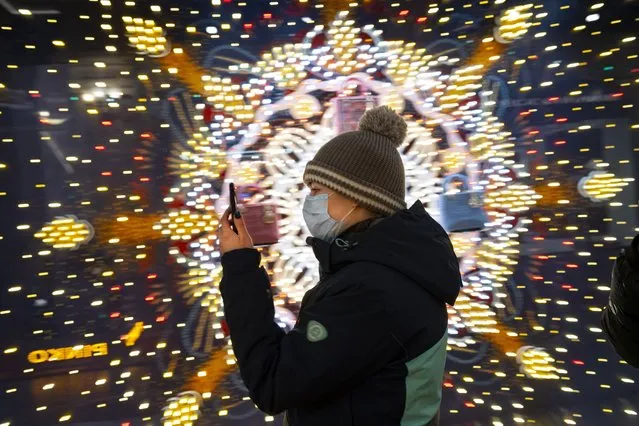 A visiter wearing a face mask to help curb the spread of the coronavirus looks at her smartphone as she walks in the GUM State Department store decorated for Christmas and New Year celebrations virtually empty due to the coronavirus pandemic in Moscow, Russia, Thursday, December 3, 2020. Russia's coronavirus vaccine Sputnik V will be available for people in high-risk groups at 70 medical facilities in Moscow starting on Saturday. According to Moscow Mayor Sergei Sobyanin, those working in education and medical facilities, along with municipal workers, can get the shots. (Photo by Alexander Zemlianichenko/AP Photo)