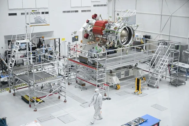 A worker wears a clean room suit as they walk past a propulsion component of the Europa Clipper spacecraft while it is prepared for a mission to Jupiter’s moon Europa inside a clean room at NASA’s Jet Propulsion Laboratory (JPL) in Pasadena, California on April 11, 2023. In October 2024, NASA will launch the Europa Clipper spacecraft that will study Jupiter's moon and its underground oceans. (Photo by Patrick T. Fallon/AFP Photo)