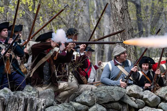 Colonial militia reenactors fire a salvo at British regular militia reenactors as they chase them through woods and fields during the Battle Road reenactment at Minute Man National Historical Park in Lincoln, Massachusetts on April 15, 2023. The reenactment recounts the battle that immediately followed the Battle of Lexington and Concord on April 19, 1775.  Re-enactors came from all over, some from England, some from Virginia and many from New England, to participate in the events of the day. (Photo by Joseph Prezioso/AFP Photo)