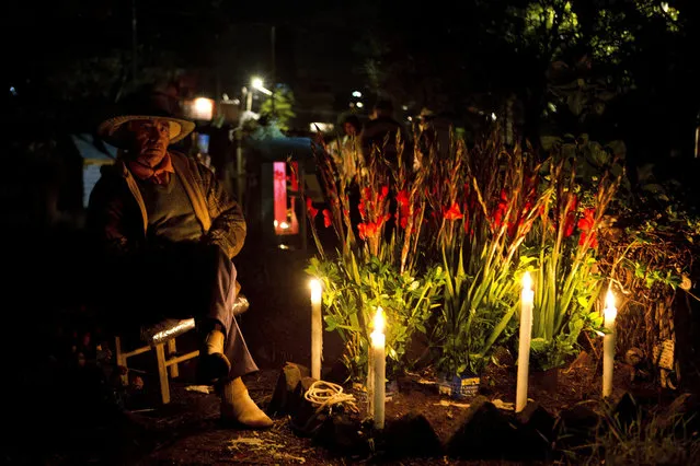 A man sits next to a child's grave decorated for Day of the Dead at the San Gregorio cemetery in Mexico City, Monday, October 31, 2016. In a tradition that coincides with All Saints Day and All Souls Day on Nov. 1 and 2, families decorate the graves of departed relatives with marigolds and candles, and spend the night in the cemetery, eating and drinking as they keep company with their deceased loved ones. (Photo by Eduardo Verdugo/AP Photo)
