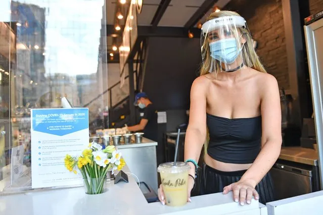 Felicity Whiston, wearing a face mask and guard, whilst serving drinks at take away restaurant Kuula Poke in Birmingham, England on June 15, 2020, as non-essential shops in England open their doors to customers for the first time since coronavirus lockdown restrictions were imposed in March. (Photo by Jacob King/PA Images via Getty Images)
