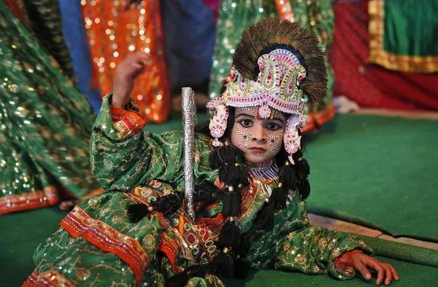An Indian artist reacts to the camera while performing “Raas Leela”, or a dance that reenacts important scenes between Hindu God Krishna and cow-herd girls, inside a Hindu holy man's camp at Sangam, the confluence of the Rivers Ganges, Yamuna and mythical Saraswati during the annual traditional fair of “Magh Mela” in Allahabad, India, Sunday, January 18, 2015. (Photo by Rajesh Kumar Singh/AP Photo)