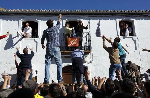 People try to catch ham legs thrown from a house during the annual San Antonio Abad (Saint Anton Abbott) festival in Trigueros, southwest Spain January 25, 2015. (Photo by Marcelo del Pozo/Reuters)