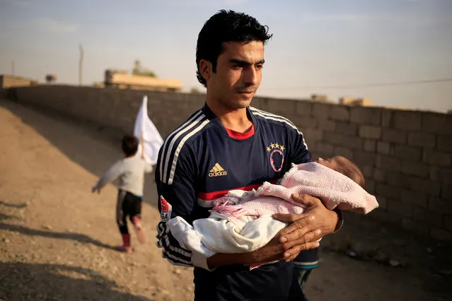 A man who is fleeing the fighting between Islamic State and Iraqi army in Mosul carries his son in Samah district, eastern Mosul, Iraq November 12, 2016. (Photo by Zohra Bensemra/Reuters)