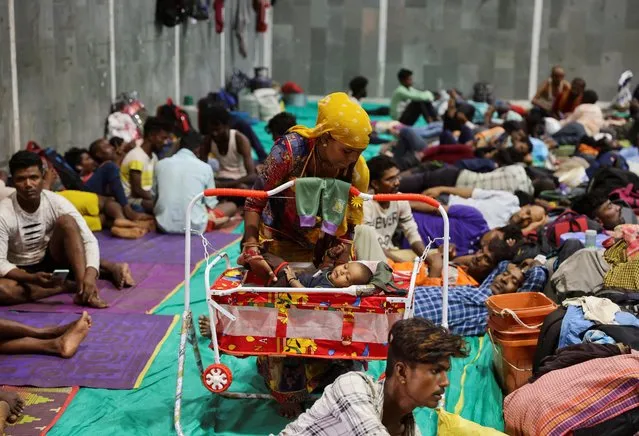 Laxmi Kumar places her three year old son Arvind inside a cradle at a temporary shelter for people evacuated from Kandla port, before the arrival of cyclone Biparjoy, in Gandhidham, in the western state of Gujarat, India on June 13, 2023. (Photo by Francis Mascarenhas/Reuters)