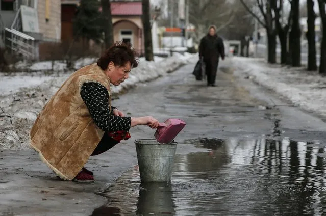 A woman gathers water from a puddle into a bucket in Donetsk, January 31, 2015. (Photo by Maxim Shemetov/Reuters)