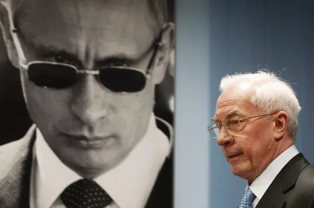 Ukraine's former Prime Minister Mykola Azarov walks past a portrait of Russia's President Vladimir Putin as he attends a news conference to present his new book in Moscow February 4, 2015. Interpol has put ousted Ukrainian president Viktor Yanukovich and two members of his former government on the international wanted list at the behest of Ukraine, according to a notice on its website on January 12. (Photo by Sergei Karpukhin/Reuters)