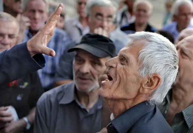 A pensioner argues with an official as he tries to enter a National Bank branch to receive part of his pension in Athens, Greece, July 6, 2015. (Photo by Christian Hartmann/Reuters)