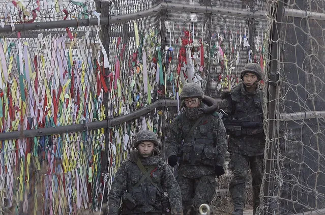 South Korean army soldiers patrol by ribbons, wishing for the reunification of the two Koreas, attached on the barbed-wire fence in Paju, near the border with North Korea, South Korea, Wednesday, January 6, 2016. North Korea said it conducted a powerful hydrogen bomb test Wednesday, a defiant and surprising move that, if confirmed, would be a huge jump in Pyongyang's quest to improve its still-limited nuclear arsenal. (Photo by Ahn Young-joon/AP Photo)