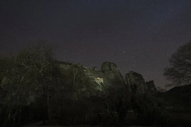 The Holy Monastery of Agios Nikolaos stands on a rock above the night sky near Kalabaka, in central Greece, Wednesday, February 1, 2023. The ancient orthodox Christian monastic community in Meteora is situated on top of vertical rock formations that average 1,000 feet in height and is one of Greece's holiest site as well as the country's environmentally protected arias. Some monasteries still serve a populated by monks and nuns. (Photo by Petros Giannakouris/AP Photo)