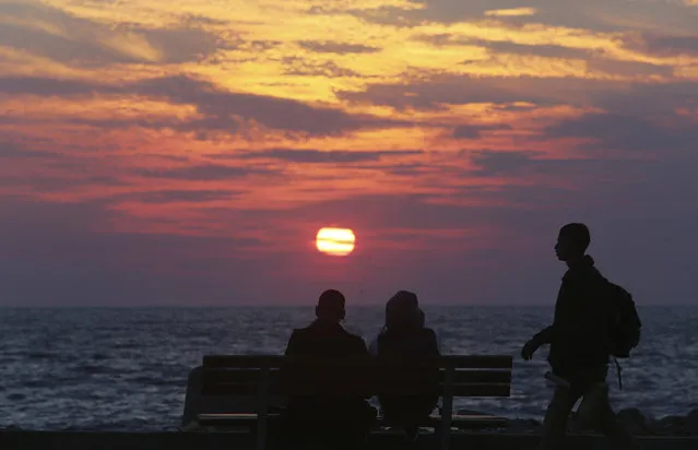 Palestinians enjoy sunset over the water of the Mediterranean Sea at the fisherman's port in Gaza City, northern Gaza Strip, Monday, February 16, 2015. (Photo by Adel Hana/AP Photo)