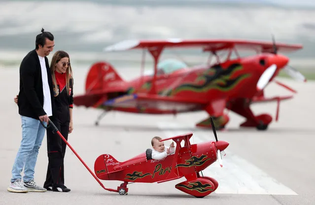 Turkey's only female aerobatic pilot Semin Ozturk Sener, 30, poses with her 8-month-old baby bay Pars sitting in his little toy plane and her husband Cem Sener, in Eskisehir, Turkey on May 06, 2021. Semin Ozturk Sener following in the footsteps of his father Ali Ismet Ozturk who was a professional aerobatic pilot, conducts her trainings at Sivrihisar International Sportive Aviation Center. She generally spends time at apron with her son and husband, Cem Sener, after her training flights. (Photo by Ali Atmaca/Anadolu Agency via Getty Images)