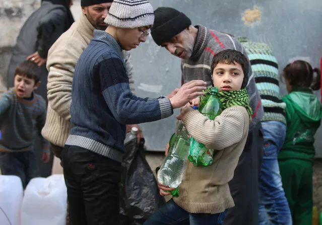 Civilians fill containers and bottles with water in a rebel-held besieged area of Aleppo, Syria December 10, 2016. (Photo by Abdalrhman Ismail/Reuters)