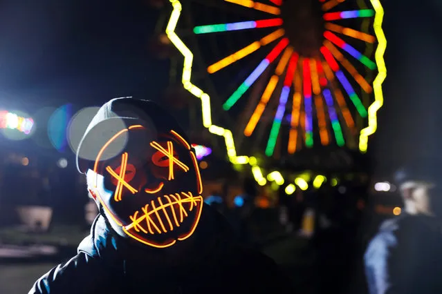 A participant is pictured in front of a Ferris wheel during a Halloween event at an amusement park in Ulaanbaatar, Mongolia on October 31, 2018. (Photo by B. Rentsendorj/Reuters)