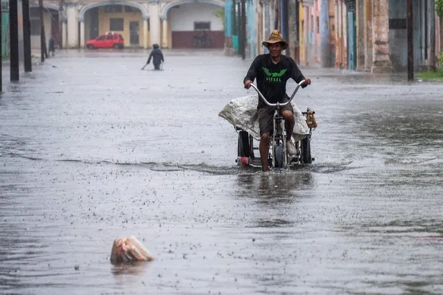 A man rides a tricycle through a flooded street in Havana, on Augusto 29, 2023, during the passage of tropical storm Idalia. Tropical Storm Idalia strengthened into a hurricane this Tuesday and forecasters are forecasting it to become “extremely dangerous” before making landfall on Wednesday in Florida, US. (Photo by Yamil Lage/AFP Photo)