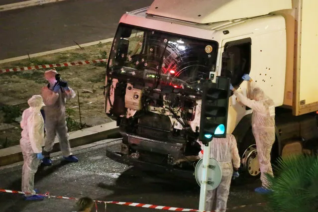 Authorities investigate a truck after it plowed through Bastille Day revelers in the French resort city of Nice, France, Thursday, July 14, 2016. France was ravaged by its third attack in two years when a large white truck mowed through revelers gathered for Bastille Day fireworks in Nice, killing at dozens of people as it bore down on the crowd for more than a mile along the Riviera city's famed seaside promenade. (Photo by Sasha Goldsmith via AP Photo)
