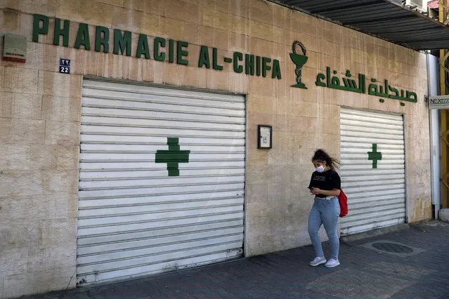 A woman passes by a closed pharmacy in Beirut, Lebanon, Friday, June 11, 2021. Pharmacies across Lebanon began a two-day strike Friday, protesting severe shortages in medicinal supplies that is increasingly putting them in confrontation with customers and patients searching for medicines. The shortages are affecting everything from medicines for chronic illnesses to pain relievers to infant milk. (Photo by Bilal Hussein/AP Photo)