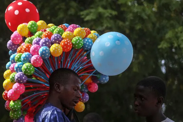 A Nigerian balloon vendor displays his wares at the celebration of the wedding of 1800 couples at Kano Central Mosque, Kano State, Nigeria on October 13, 2023. The mass wedding is sponsored by the Kano State government in Nigeria to help widows and divorcees get remarried. (Photo by Kola Sulaimon/AFP Photo)
