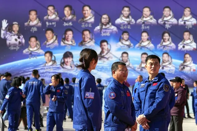 Staff members gather near a billboard depicting Chinese astronauts on the past Shenzhou missions after Chinese astronauts for the upcoming Shenzhou-17 mission met with the press at the Jiuquan Satellite Launch Center in northwest China, Wednesday, October 25, 2023. (Photo by Andy Wong/AP Photo)