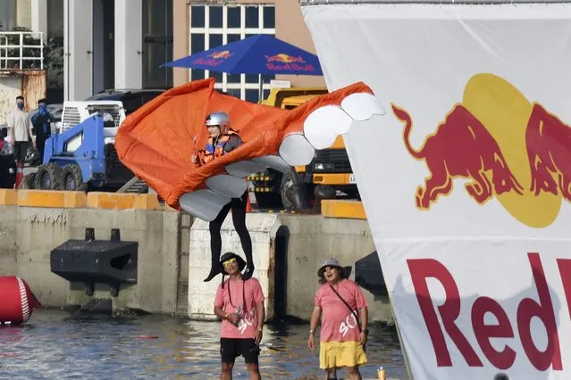 A team member jumps from a platform with a man made flying machine into the harbor in Taichung, a port city in central Taiwan on Sunday, September 18, 2022. Pilots with homemade gliders launched themselves into a harbor from a 20-foot-high ramp to see who could go the farthest before falling into the waters. It was mostly if not all for fun as thousands of spectators laughed and cheered on 45 teams competing in the Red Bull “Flugtag” event held for the first time. (Photo by Szuying Lin/AP Photo)