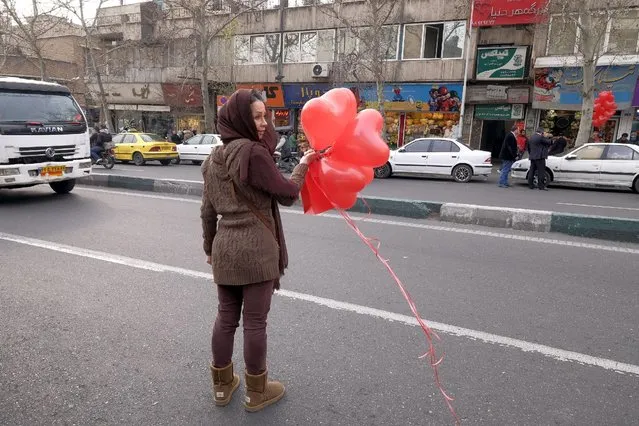 Iranian woman holding heart-shaped balloons waits for a taxi after her shopping for Valentine's day in Tehran, Iran, February 14, 2016. (Photo by Raheb Homavandi/Reuters/TIMA)