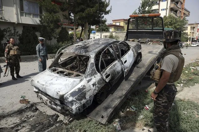 Security personnel inspect a damaged vehicle where rockets were launched in Kabul, Afghanistan, Tuesday, July 20, 2021. At least three rockets hit near the presidential palace on Tuesday shortly before Afghan President Ashraf Ghani was to give an address to mark the Muslim holiday of Eid-al-Adha. (Photo by Rahmat Gul/AP Photo)
