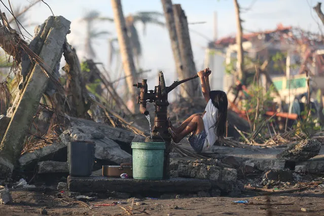 A young typhoon survivor fetches water from a hand pump at typhoon-ravaged Tolosa town, Leyte province, central Philippines Monday, December 9, 2013. One month since Typhoon Haiyan, signs of progress in this shattered Philippine city are mixed with reminders of the scale of the disaster and the challenges ahead. Tens of thousands are living amid the ruins of their former lives, underneath shelters made from scavenged materials and handouts. (Photo by Aaron Favila/AP Photo)