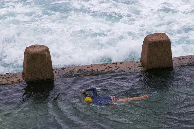 A person swims in a rock pool while large waves approach at Coogee Beach, as heavy rains affect Sydney, Australia on October 6, 2022. (Photo by Loren Elliott/Reuters)