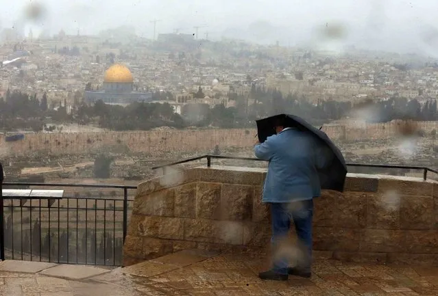 The Dome of the Rock is seen in the background as a tourist holds her umbrella during a gust of wind outside Jerusalem's Old City February 19, 2015. (Photo by Ammar Awad/Reuters)